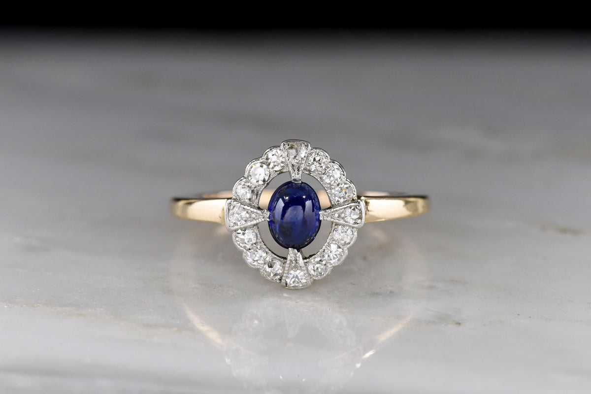 Edwardian-Era Gold and Platinum Cluster Ring with a Cab Cut Sapphire Center