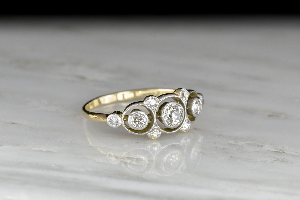 Belle Époque Gold and Platinum Ring with a Unique Floating Three-Stone Bezel Design